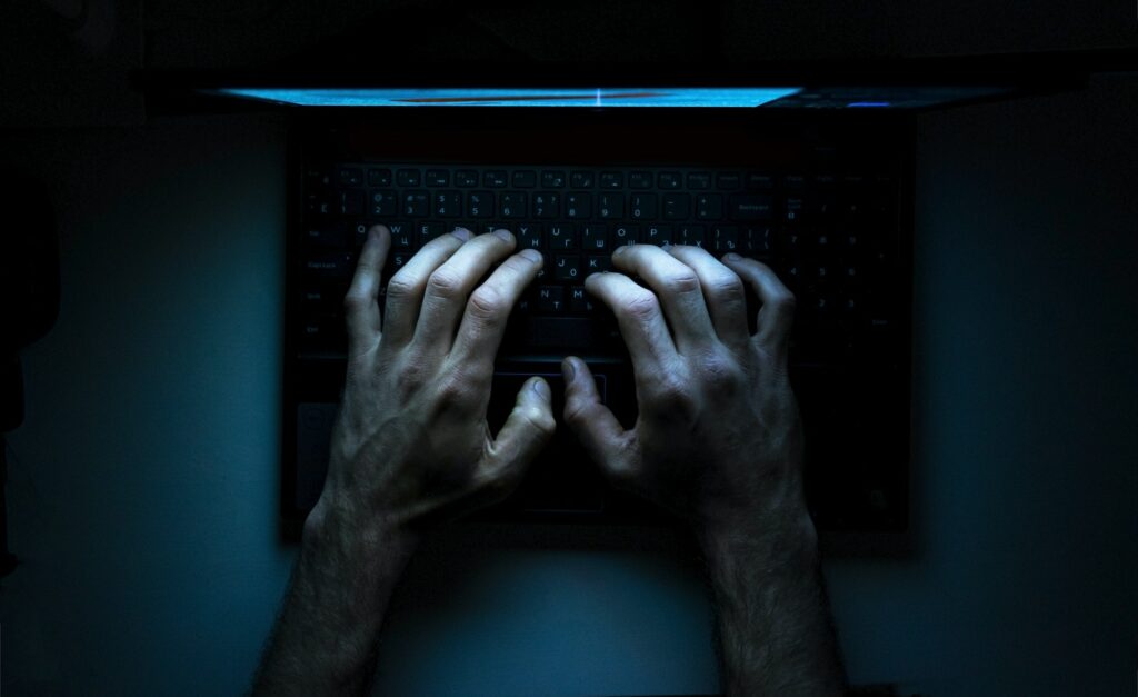 hands typing on keyboard dark room